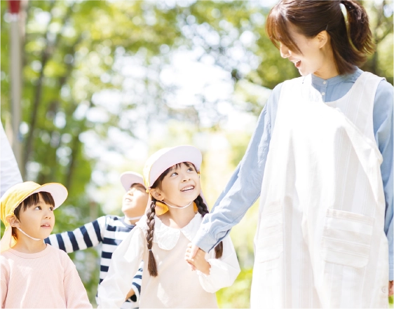 園庭を歩く幼稚園教諭と子どもたち