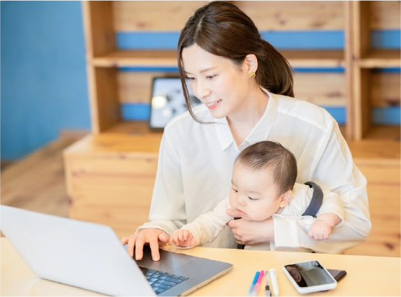 子どもを抱きながらオンライン交流会に参加する学生