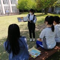 保育科「子どもと言葉」の授業でキャンパスの芝生にて絵本の読み聞かせを実施しました